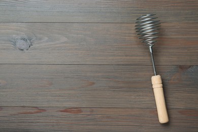 Photo of One metal whisk on wooden table, top view. Space for text