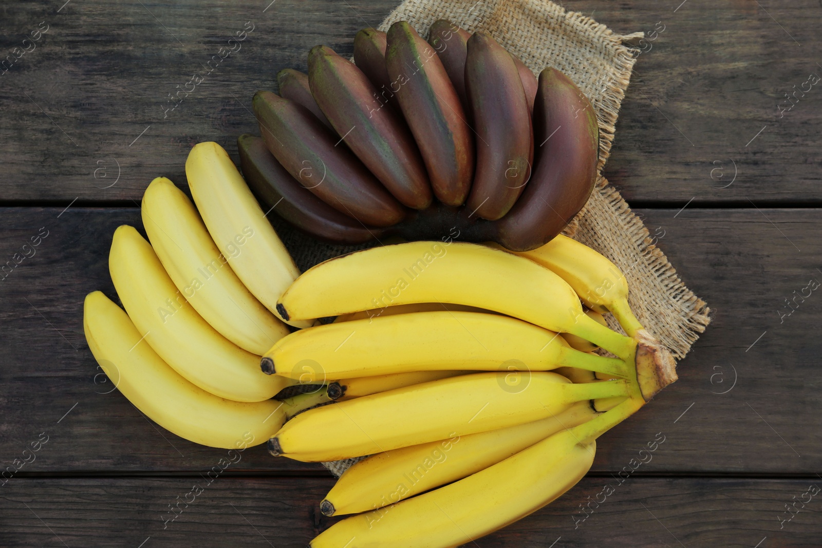 Photo of Tasty purple and yellow bananas on wooden table, flat lay