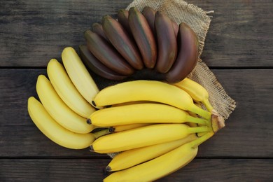 Tasty purple and yellow bananas on wooden table, flat lay