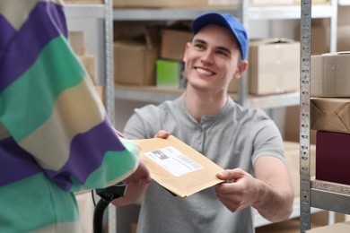 Photo of Worker giving parcel to woman at post office, focus on hands