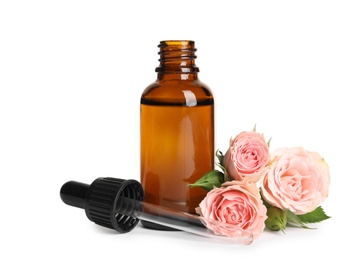 Photo of Bottle of rose essential oil and flowers isolated on white