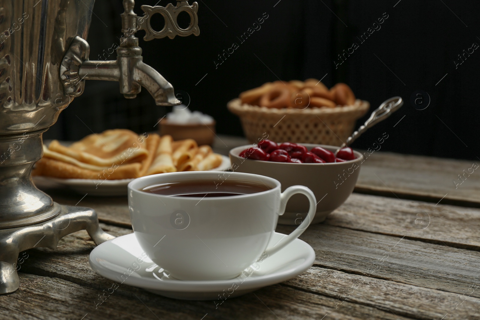 Photo of Metal samovar with cup of tea and treats on wooden table