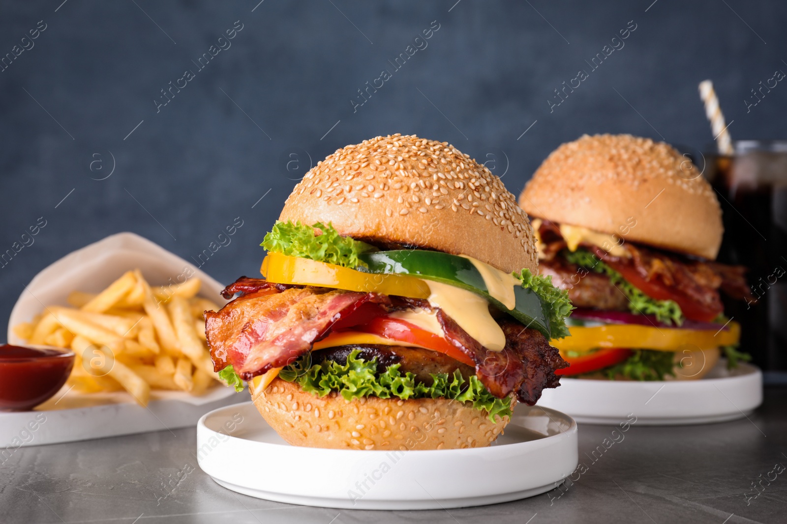 Photo of Composition with juicy bacon burger on grey table