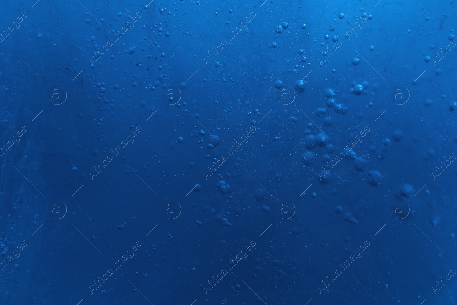 Photo of Closeup view of light blue crystal clear ice cube as background. Color tone effect