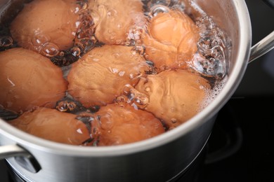 Photo of Chicken eggs boiling in pot on electric stove, closeup