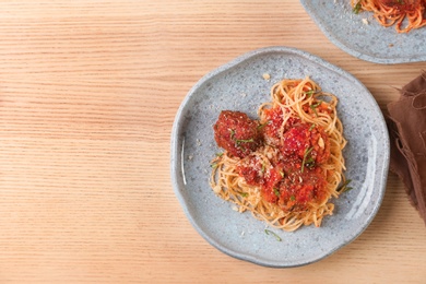 Photo of Delicious pasta with meatballs and tomato sauce on wooden background, top view
