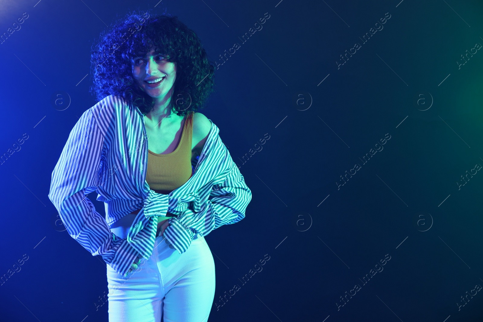 Photo of Beautiful young woman posing on color background in neon lights. Space for text