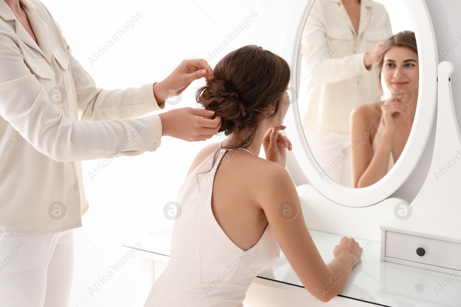 Photo of Hair stylist preparing bride for her wedding indoors