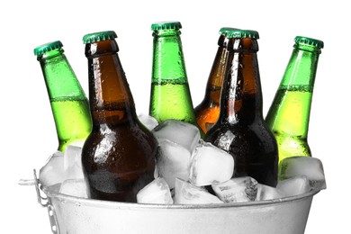 Metal bucket with different bottles of beer and ice cubes on white background