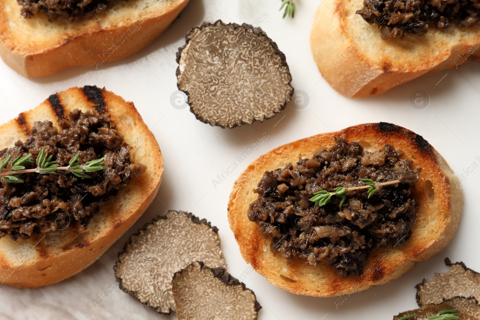 Photo of Delicious bruschettas with truffle sauce and thyme on white table, flat lay