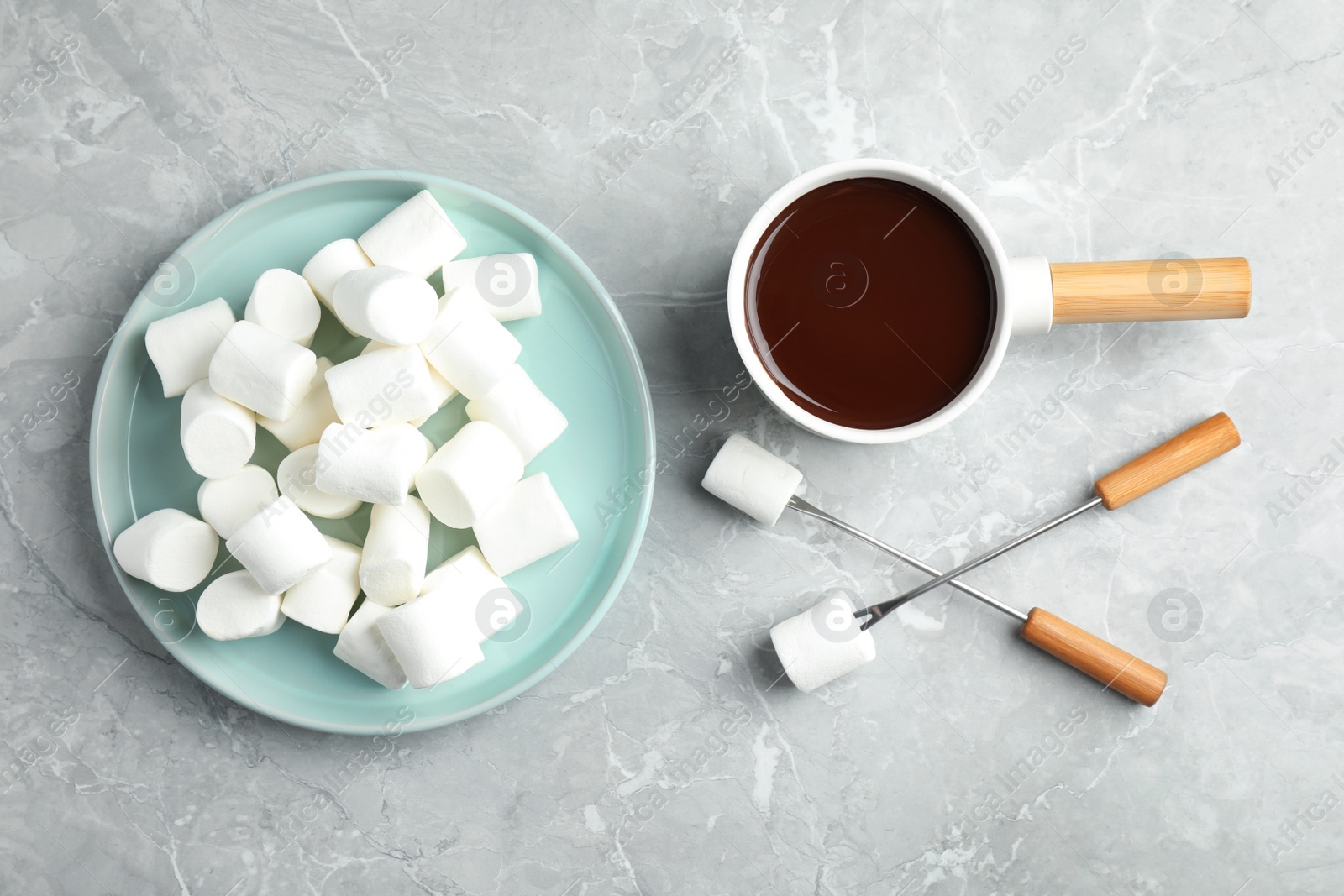 Photo of Fondue pot with dark chocolate and marshmallows on marble table, flat lay