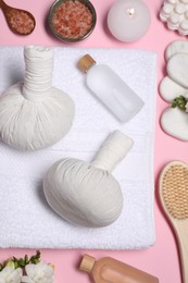 Flat lay composition with herbal massage bags and other spa products on pink background