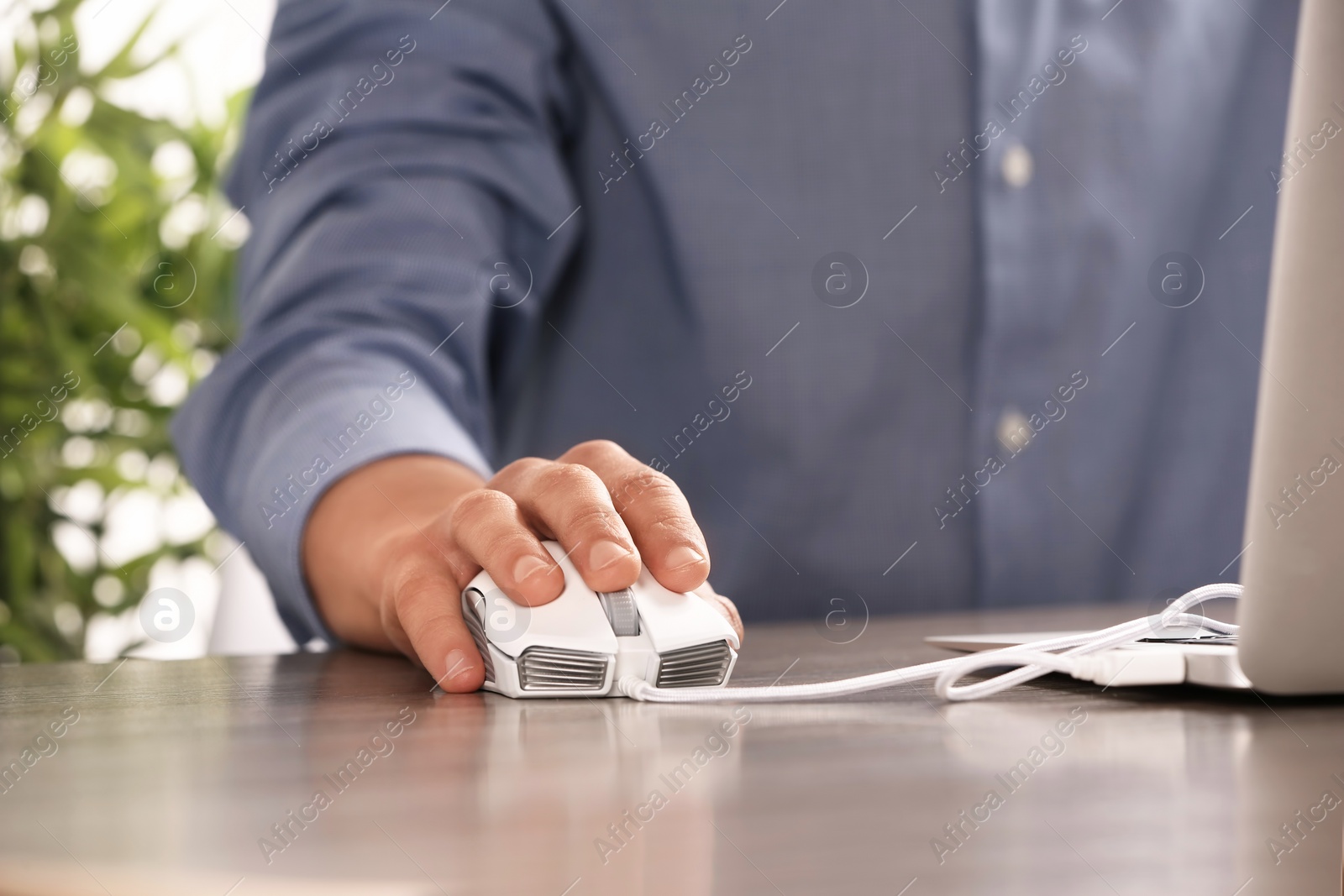 Photo of Man using computer mouse with laptop at table, closeup