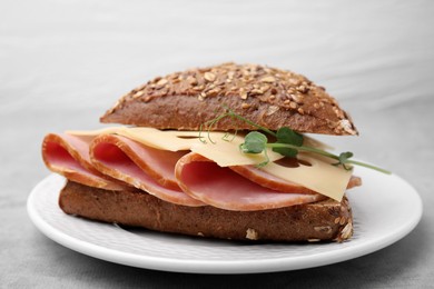 Photo of Delicious sandwich with ham and cheese on light gray table, closeup