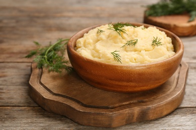 Photo of Bowl with mashed potatoes on wooden board