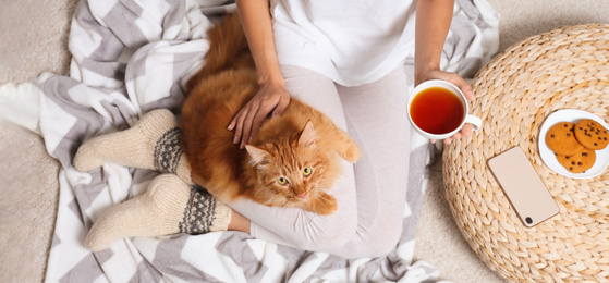 Image of Young woman with her cute pet on blanket, top view. Banner design