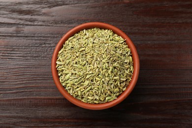 Photo of Fennel seeds in bowl on wooden table, top view