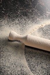 Photo of Scattered flour and rolling pin on table, above view