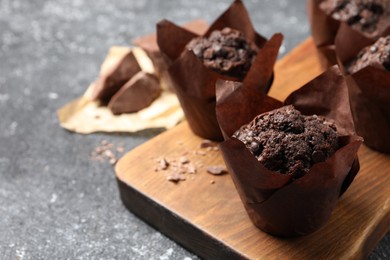 Photo of Tasty chocolate muffins on grey table, closeup. Space for text