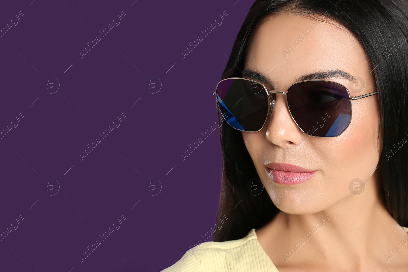 Photo of Beautiful woman wearing sunglasses on purple background, closeup. Space for text