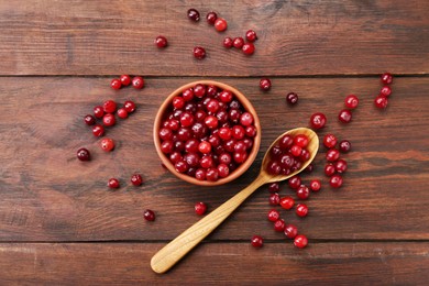 Photo of Fresh ripe cranberries in bowl and spoon on wooden table, flat lay