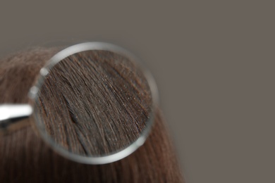 Photo of Closeup of woman with dandruff in her hair on grey background, view through magnifying glass. Space for text