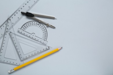 Photo of Different rulers and compass on light grey background, flat lay. Space for text