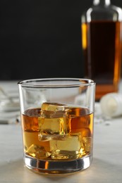 Photo of Alcohol addiction. Whiskey with ice cubes in glass on white table