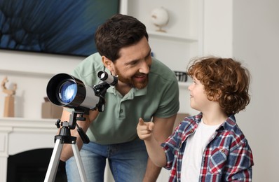 Photo of Little boy with his father using telescope to look at stars in room