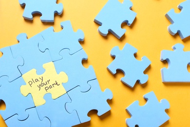 Photo of Jigsaw puzzle with phrase Play Your Part on yellow background, flat lay. Social responsibility concept