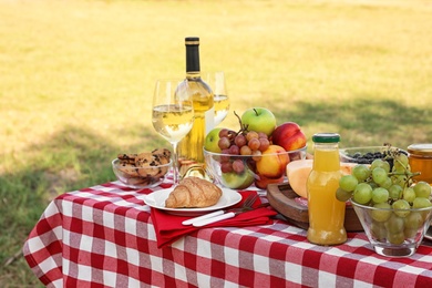 Photo of Picnic table with different tasty snacks and wine