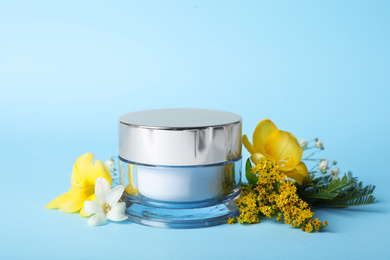 Photo of Jar of luxury face cream and plants on light blue background