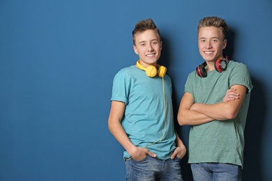 Photo of Teenage twin brothers with headphones on color background. Space for text
