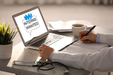 Image of Doctor with laptop at table in office, closeup. Interns wanted