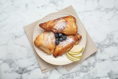 Photo of Fresh tasty puff pastry with sugar powder, pear and blueberries served on white marble table, top view