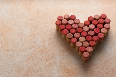 Photo of Heart made of wine bottle corks on textured table. Space for text