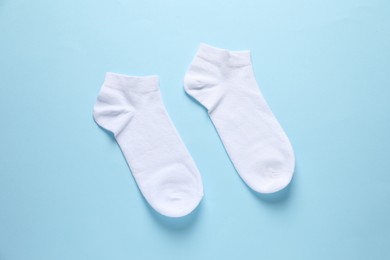 Photo of Pair of white socks on light blue background, flat lay