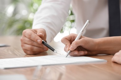 Photo of Businesspeople signing contract at table in office, closeup