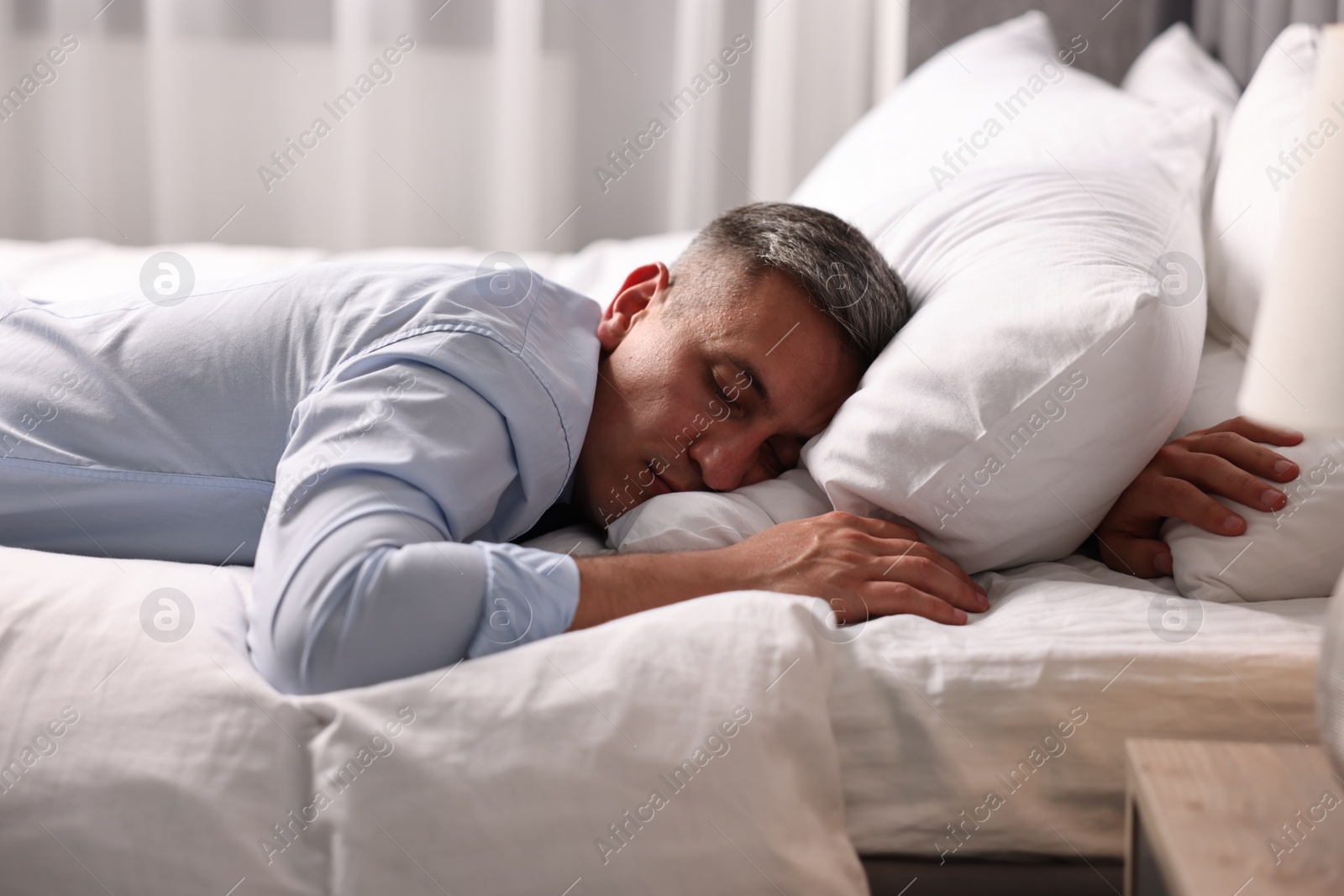 Photo of Businessman in office clothes sleeping on bed indoors