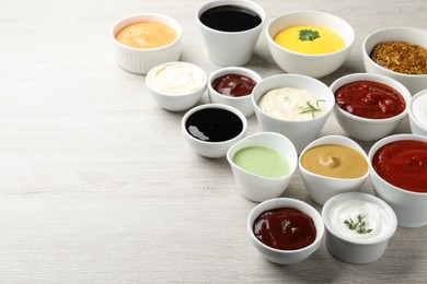 Photo of Many different sauces on white wooden table, space for text 