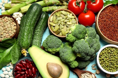Photo of Fresh vegetables and seeds on light blue wooden table, flat lay