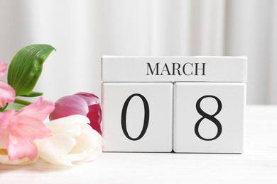 Photo of International Women's day - 8th of March. Wooden block calendar and beautiful flowers on white table