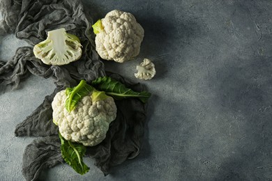 Photo of Fresh whole and cut cauliflowers on grey textured background, top view. Space for text