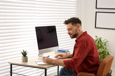 Photo of Online translation course. Man writing near computer indoors