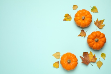 Photo of Fresh ripe pumpkins and autumn leaves on light blue background, flat lay. Space for text