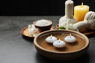 Photo of Composition with different spa products and burning candles on grey table, space for text