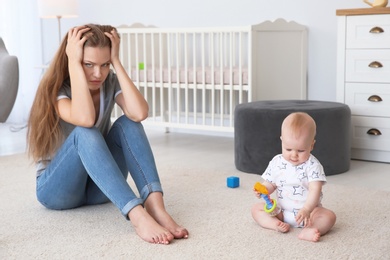 Photo of Young mother suffering from postnatal depression and cute baby girl at home