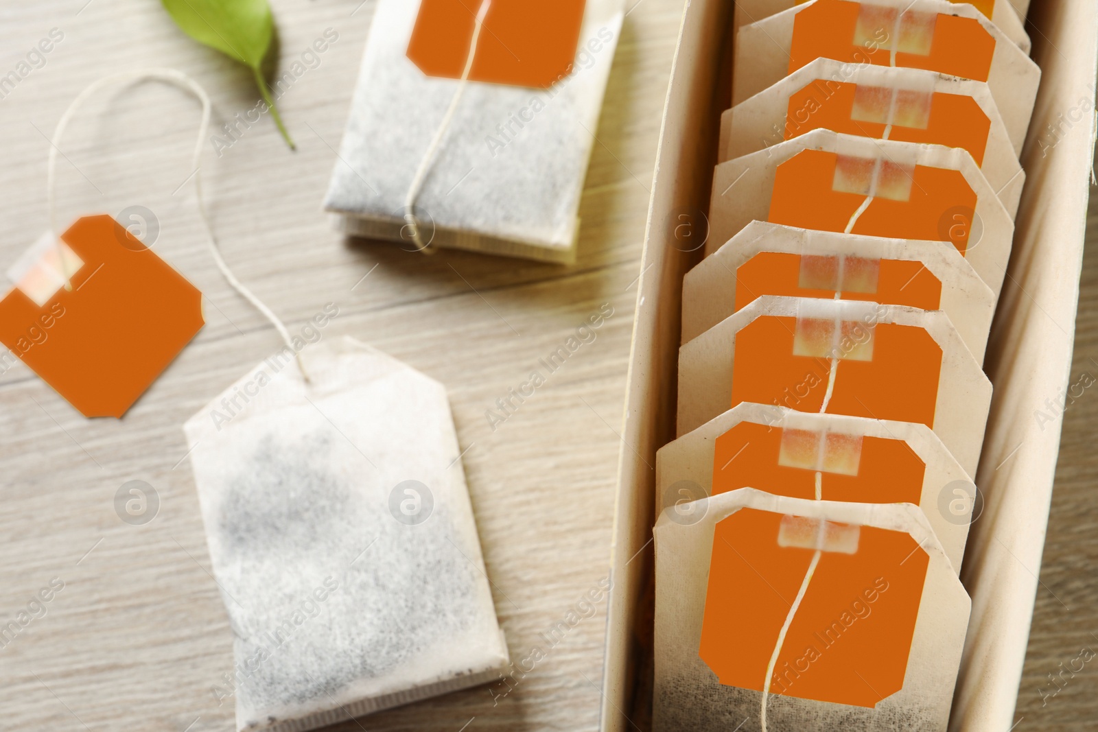 Photo of Box with paper tea bags on wooden table, closeup