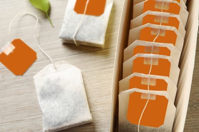 Photo of Box with paper tea bags on wooden table, closeup