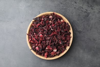 Hibiscus tea. Wooden bowl with dried roselle calyces on grey table, top view